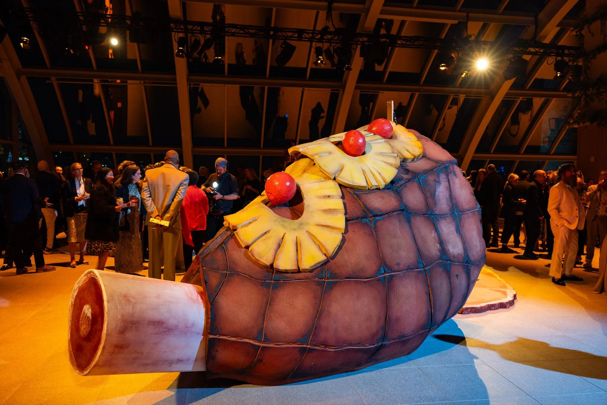 Artwork of a large, human height, ham hock with cherries and pineapples on it.
