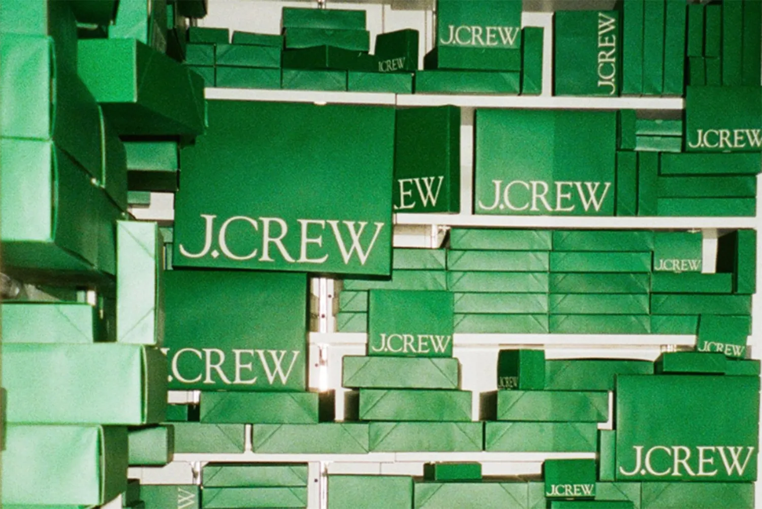 Green wrapped boxes with J.Crew logo on them stacked in shelves