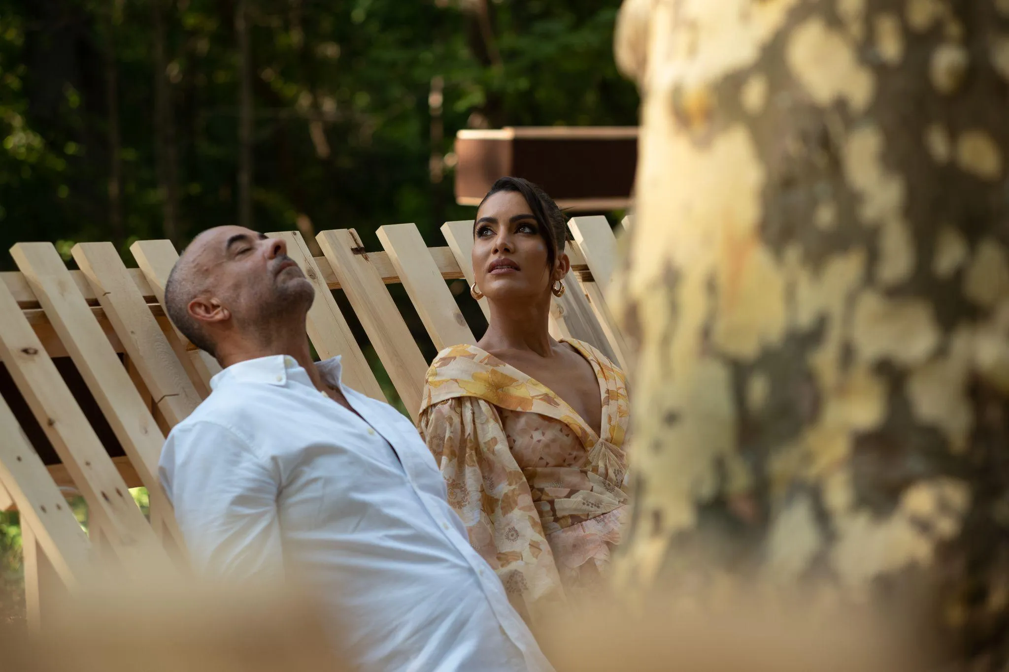 Man and woman sitting on wooden laid back seating