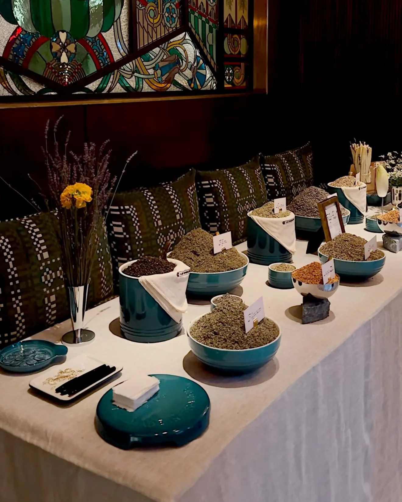 Teal Le Creuset cookware filled with dried legumes on a decorated table