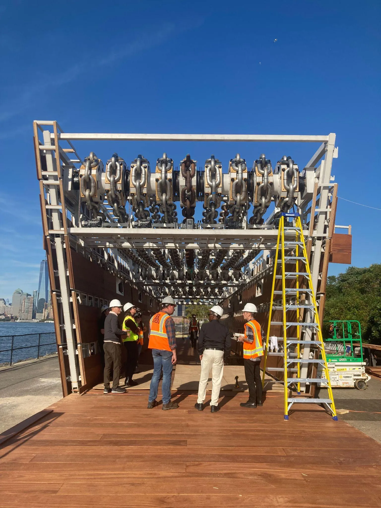Crew with hard hats and a ladder inspecting the sculpture